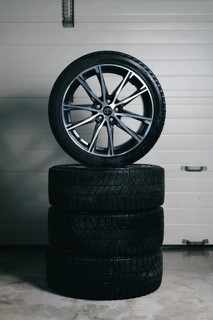 Home Car tires stacked with an alloy wheel on top in a garage setting. Perfect for automotive themes.