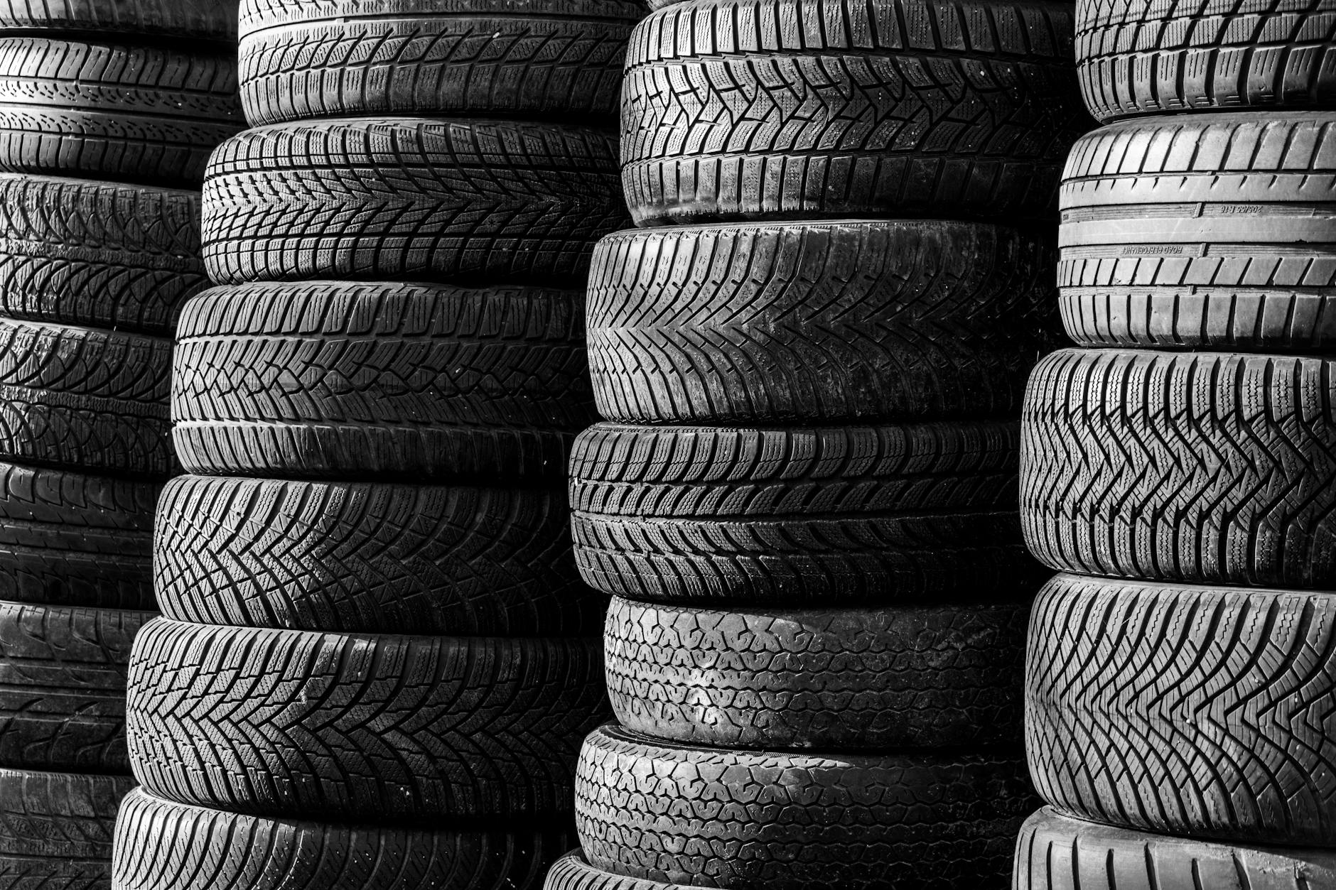 Home Black and white image of stacked vehicle tires showcasing various tread patterns.